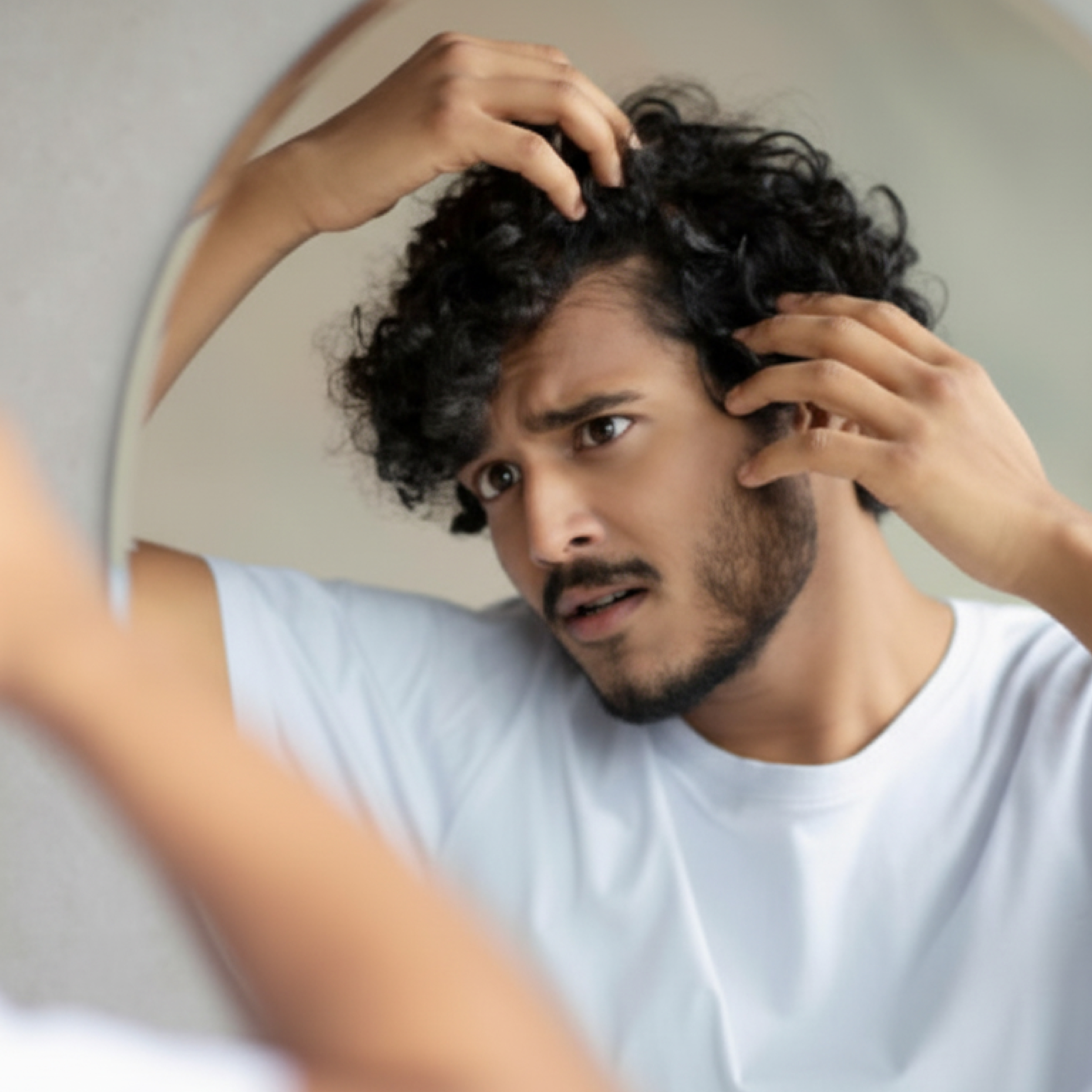 Person examining hair loss in mirror